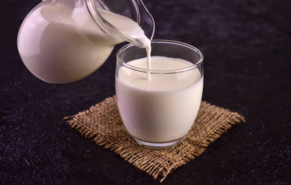 Latte Viene Versato Bicchiere Uno Sfondo Nero — Foto Stock