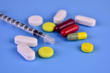 Medicines on a blue background: injection ampoules tablets and syringes.