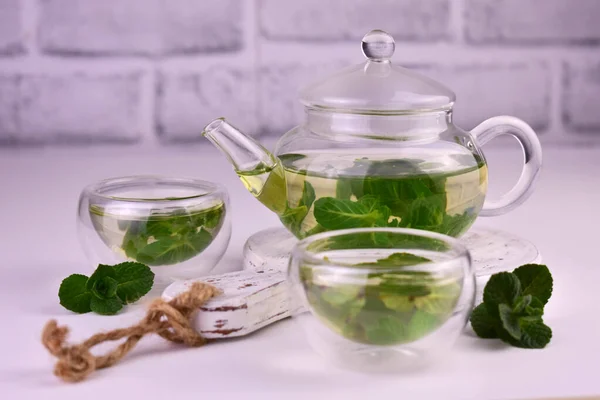 Mint tea with fresh mint leaves in a glass teapot.