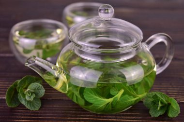 Koyu ahşap zemin üzerinde nane çayı olan çaydanlık..