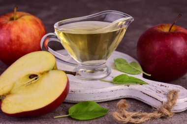 Elma sirkesi ve siyah arka planda beyaz tahta üzerinde taze elma..