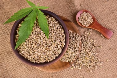 Tahta bir kasede kenevir tohumu ve kenevir yaprağı. Yukarıdan görüntüle.