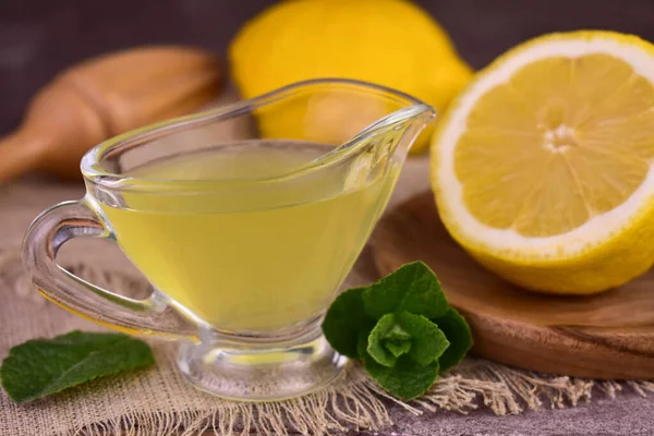 stock image Lemon juice in a gravy boat and fresh lemons.Close-up.