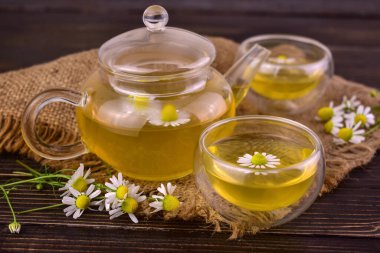 Ahşap bir arka planda çaydanlıkta papatya çayı.