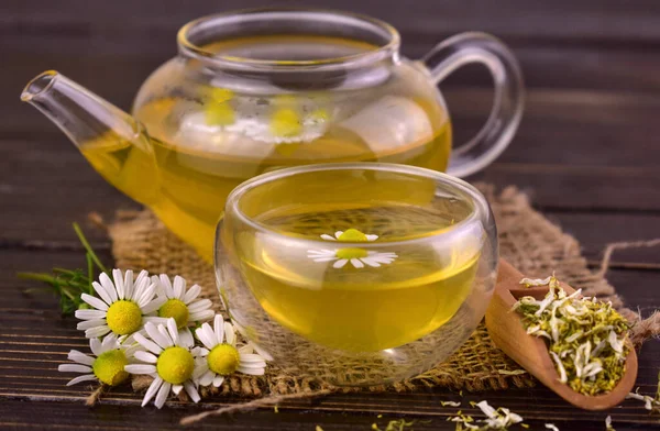 Ahşap bir arka planda çaydanlıkta papatya çayı.