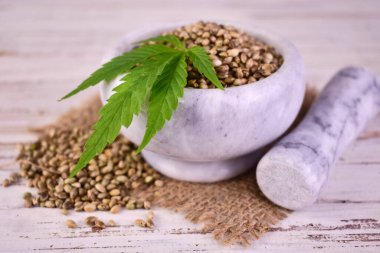 Beyaz ahşap zemin üzerinde kullanışlı kenevir tohumları olan havan topu..