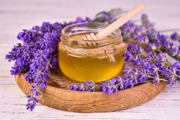 Fresh fragrant lavender honey and lavender flowers on a wooden tray.