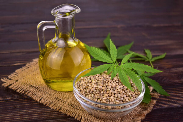 Здоровая конопляное масло и конопля семян на деревянном фоне.