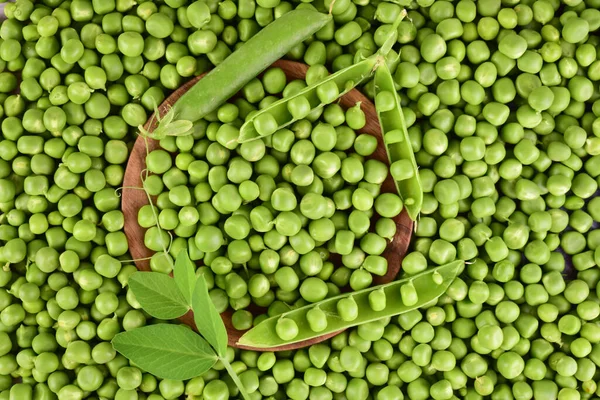 Background of green peas. Pods of green peas on a background of peeled peas. Flat lay.