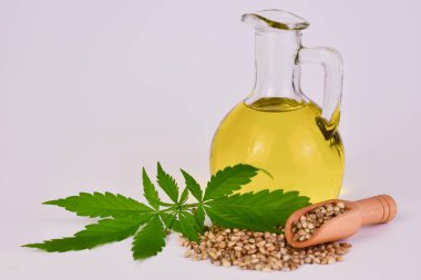 Beyaz arka planda bir sürahide kenevir tohumu yağı. Boşluğu kopyala.