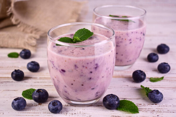 Homemade smoothie with fresh blueberries on a white wooden background.
