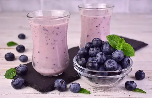 Beyaz ahşap arka planda taze yaban mersinli ev yapımı smoothie..