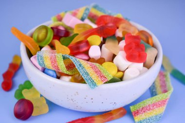 Mavi bir kasede mavi bir arka planda bir sürü farklı şeker. Yakın plan..