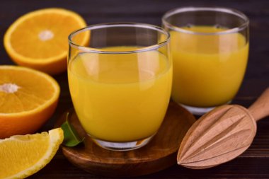 Koyu ahşap arka planda gözlüklü taze portakal suyu..