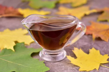 Akçaağaç şurubu, cam sos kabı ve akçaağaç yaprakları..