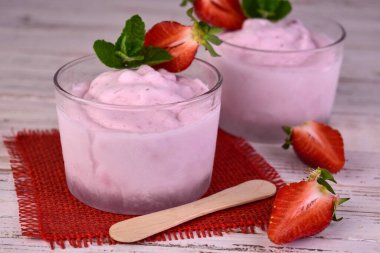 Beyaz ahşap arka planda iki porsiyon çilekli dondurma..