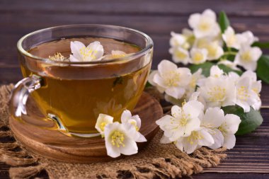 Bir fincan yasemin çayı ve koyu arkaplanda taze yasemin çiçekleri..