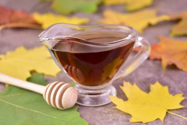 Akçaağaç şurubu, gri bir arka planda sos kabında. Yakın plan..