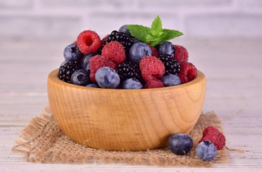 Yaban mersini, ahududu ve böğürtlen ahşap bir kasede. Yakın plan..