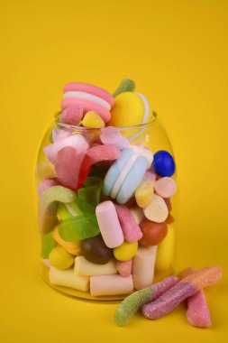 Sarı arka planda kavanozda bir sürü farklı şeker var..