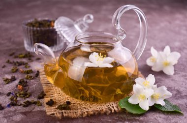 Yasemin çiçekli çay, gri arka planda yaldızlı bir çaydanlıkta.