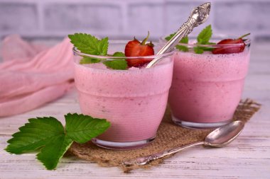 Hafif ahşap arka planda bir bardakta çilekli puding..