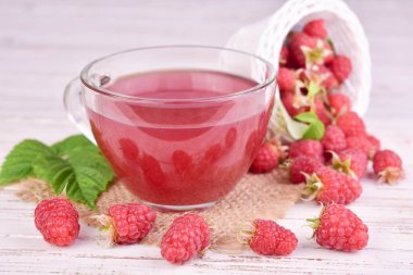 Ahşap arka planda cam bir fincanda ahududu çayı. Yakın plan..