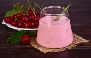 Koyu ahşap bir masada, bardakta, sağlıklı vişneli smoothie. Yakın plan..