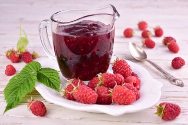 Beyaz ahşap arka planda cam soslu ahududu reçeli..