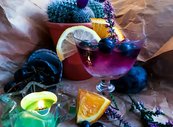 背景に果物やサボテンに囲まれたガラスの中に氷のキューブとブラックベリーアルコール飲料 — ストック写真