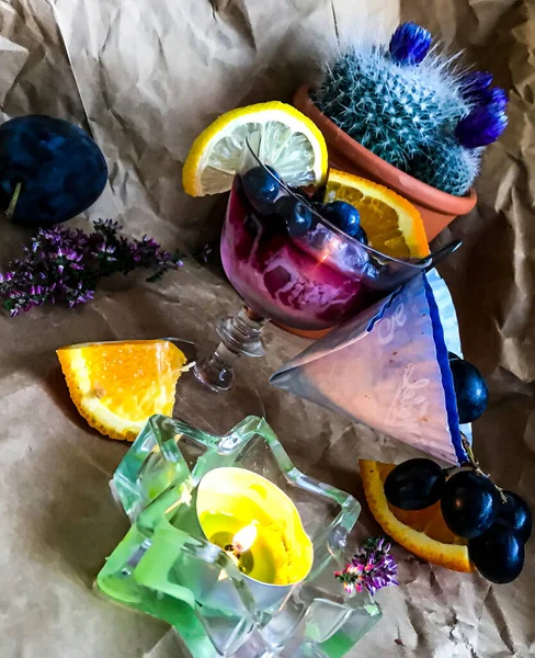 背景に果物やサボテンに囲まれたガラスの中に氷のキューブとブラックベリーアルコール飲料 — ストック写真