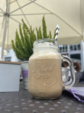 Ana cadde manzaralı cam kavanozda soğuk kahve.