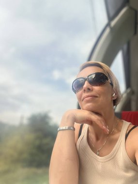 Kısa sarı saçlı ve güneş gözlüklü güzel bir genç kadın.