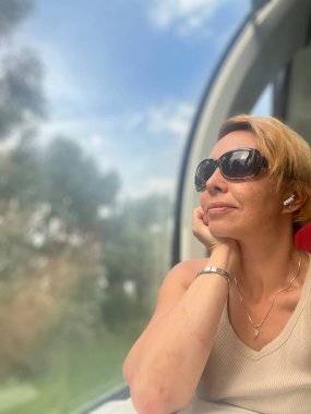 Kısa sarı saçlı ve güneş gözlüklü güzel bir genç kadın.