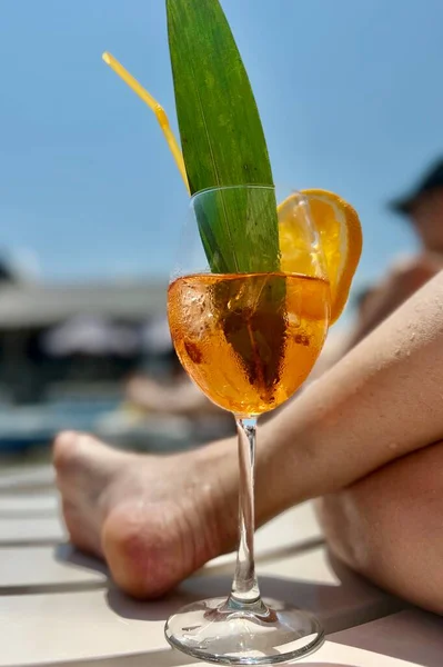 Zbliżenie Kobiecej Nogi Trzymającej Szklankę Soku Pomarańczowego Kawałek Cytryny Plaży — Zdjęcie stockowe