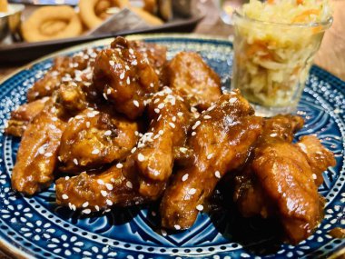 Teriyaki tavuk kanadı kiraz sosu altında susam tohumu ve lahana turşusu. 