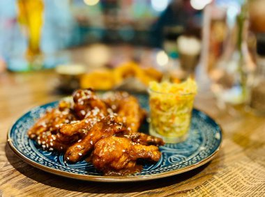 Teriyaki tavuk kanadı kiraz sosu altında susam tohumu ve lahana turşusu. 