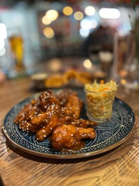 Teriyaki tavuk kanadı kiraz sosu altında susam tohumu ve lahana turşusu. 