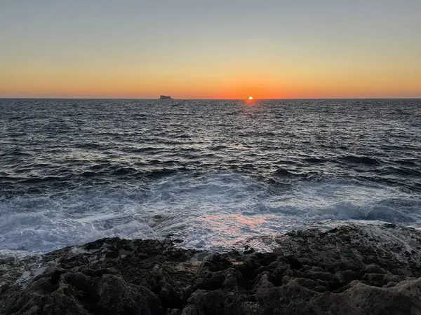 Sunset on the Mediterranean Sea with a far away seen island in the distance at Malta
