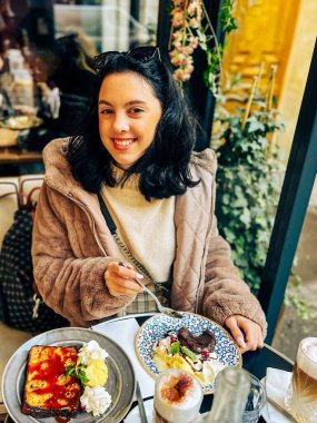 Genç, güzel esmer kadın Fransa, Paris 'teki sokak kafesinde dondurma yiyor. Açık hava yaşam tarzı portresi 