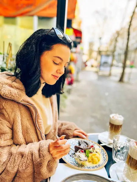 Genç, güzel esmer kadın Fransa, Paris 'teki sokak kafesinde dondurma yiyor. Açık hava yaşam tarzı portresi 