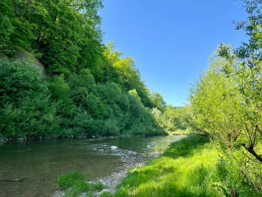 Nehre bitişik sarp kayalıklar güzel yeşillikler ve ağaçların arasında.