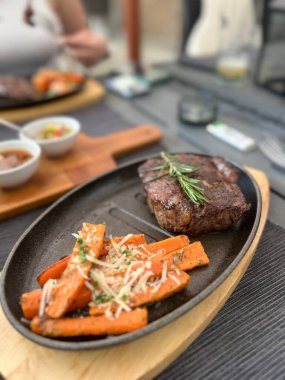 Baharatlı ızgara biftek, biberiye ve ahşap tahtada biber..