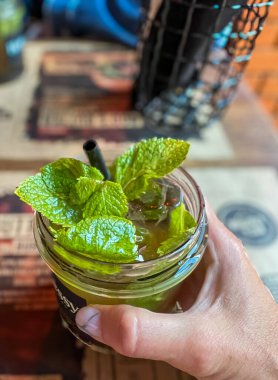Bardakta mojito kokteyli, ahşap bar masasında nane yaprakları. 
