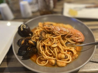 Malta restoranında ahşap bir masada midyeli ve karidesli spagetti.