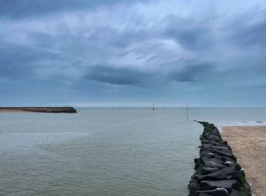 Fransa, Normandie 'de dalgalı bir suyla denizin üzerinde dramatik bulutlu bir gökyüzü.