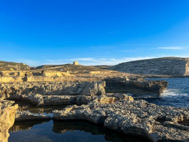 Gozo adasının kayalık sahillerinde güzel bir gün batımı, Malta