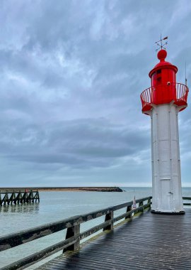Fransa 'nın Normandiya şehrinde, üzerinde mavi gökyüzü ve yağmurlu bulutlar bulunan kırmızı deniz feneri.. 