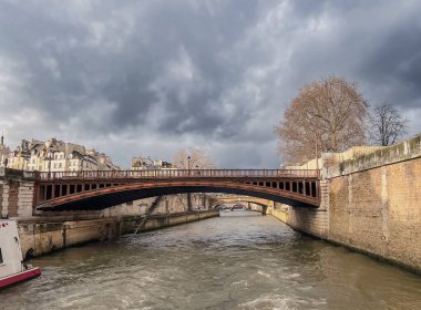 Paris, Fransa 'daki Seine Nehri. Bulutlu gökyüzü ile güzel bir şehir. Evlerin manzarası ve bir teknenin köprüsü..