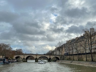 Paris, Fransa 'daki Seine Nehri. Bulutlu gökyüzü ile güzel bir şehir. Evlerin manzarası ve bir teknenin köprüsü..